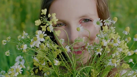 Close-up of a girl's face looking through a bouquet of wildflowers. Stock Footage 156070245
