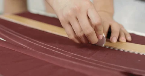 A close-up of girl's hand designer line charting on the fabric using patterns Stock Footage