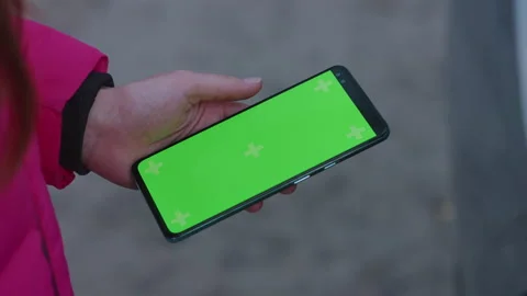 Close up of girls hand using smartphone outdoors with empty green screen Stock Footage 220679731