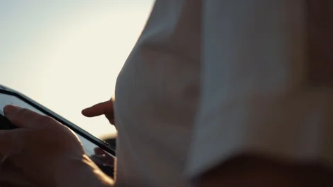Close-up of a girl's hand working with a tablet computer at sunset and against Stock-Footage 91849953