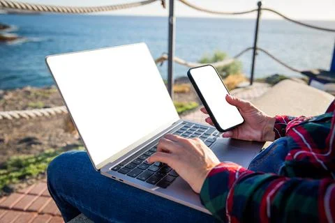 Close up of girl's hands using computer and smartphone, screens mockup. Stock Photos