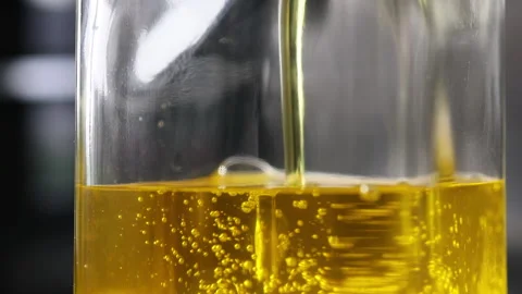 Close up of glass bottle being filled with extra virgin olive oil. Video stock 224882889