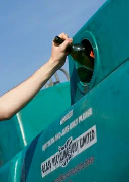 CLOSE UP OF GLASS BOTTLE BEING PLACED IN RECYCLING BANK Stock Photos