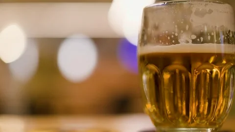 Close up of glass with cold draft lager beer on table in evening restaurant.. Stock Footage 332628573