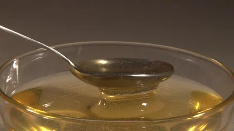 Close up of glass plate full of honey stiring with a spoon shooted from side 動画素材 220651753