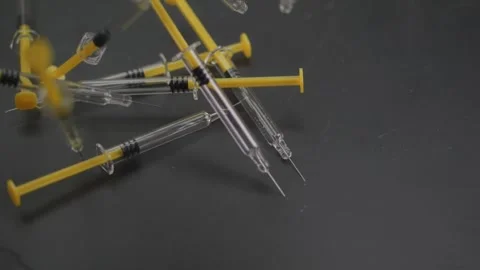 Close-up of glass syringes dropping onto a surface, captured in slow motion.. Video stock 303628035