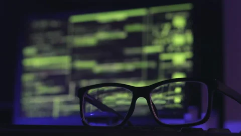 Close-up of glasses on the keyboard, computer code on the background. Stock Footage 203799109