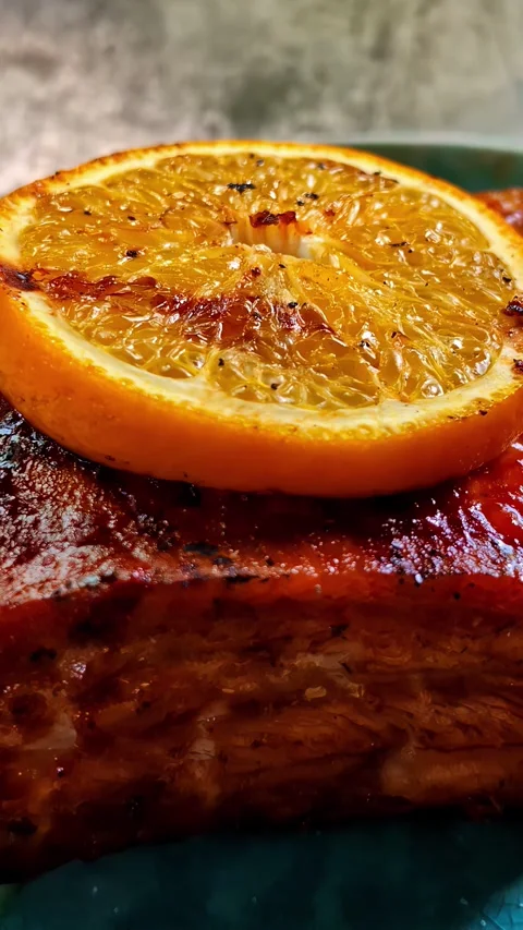 Close up of glazed grilled ham with caramelized orange slice on dark ceramic Stock Footage 336238936