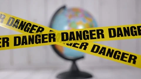 A close-up of a globe with a yellow warning tape with the inscription DANGER. Stock Footage 329913606