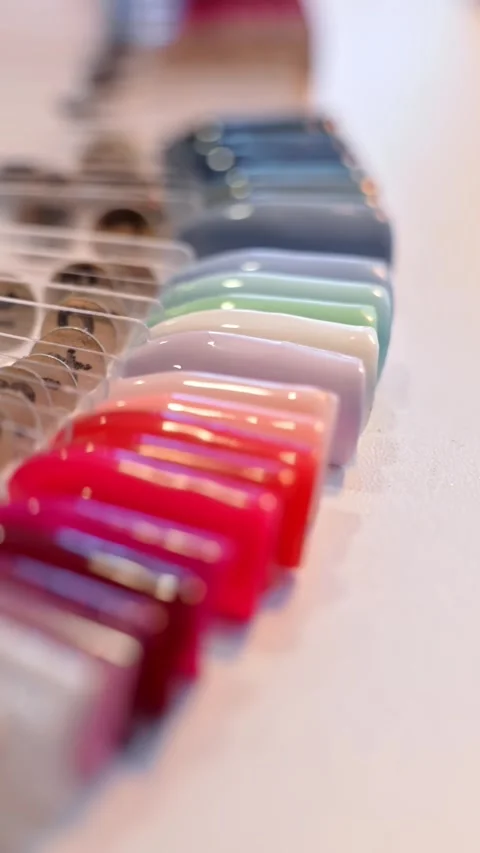 Close-up of a glossy nail color sample palette in a beauty salon, showing 動画素材 333651990