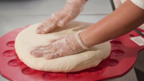 A close-up of a gloved baker's hands shaping dough on a mold for subsequent Video stock 229693856