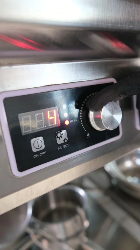 Close-up of a gloved hand adjusting the temperature dial on a modern, stainless Stock Footage 318316928