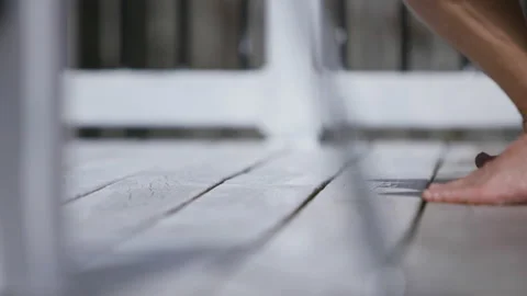 Close up of gloved hand and bare feet as man paints deck Stock Footage 131102628