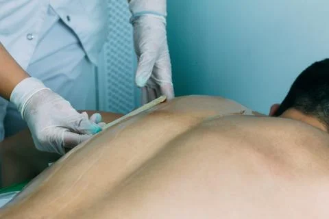 Close up of a gloved hand applying depilatory cream to a man in shape, concep Stock Photos