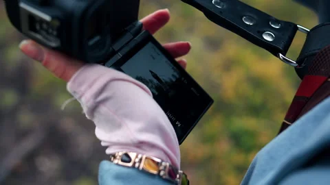 Close-up of gloved hand holding compact camcorder with flip-out screen outdoors Stock Footage 340109048