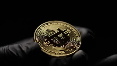 Close-up of a gloved hand holding a physical Bitcoin with dramatic lighting Video stock 302289117