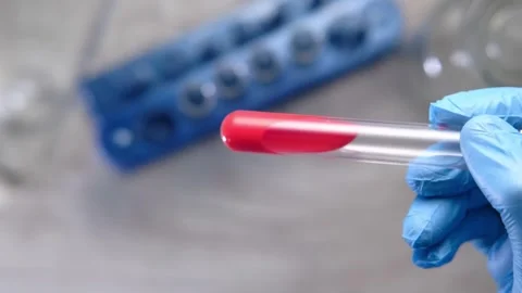 Close up of gloved hand holding test tube with red liquid in laboratory set.. Video stock 333031932