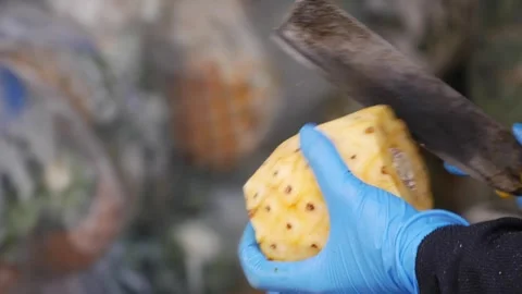 Close up of a gloved hand peeling a pineapple with a knife at a market stall. Ve Stock Footage 340881079