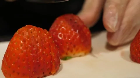 Close-Up of a Gloved Hand Preparing a Fresh Strawberry on a Cutting Board Stock Footage 345292877