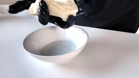 Close-up of a gloved hand squeezing wet bread, demonstrating liquid extract.. Stock Footage 318411051