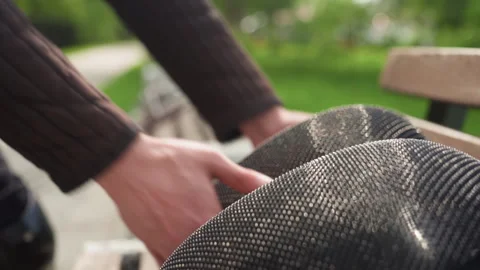 Close up of gloved hands adjusting black mesh fabric texture on bench in outdoor Stock Footage 345080506
