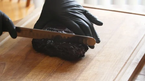 Close up of gloved hands cutting BBQ pork burnt ends on a wood cutting board Stock Footage 91339162