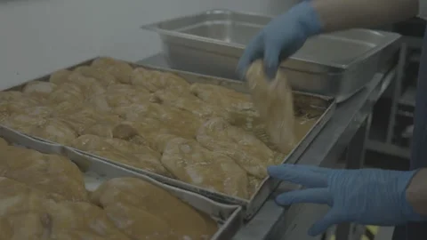 Close-up of gloved hands handling raw glazed poultry 動画素材 327353339