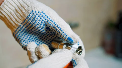 Close-up gloved hands a man is sealing tape wrap around iron water tap screw Stock Footage 104144916