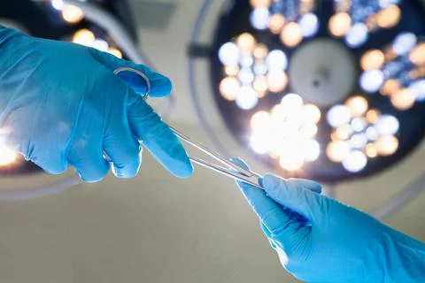 Close-up of gloved hands passing the surgical scissors, operating room, hos.. Stock Photos
