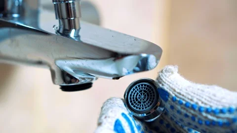 Close - up of gloved hands plumber sets aerator. Видео 104404857