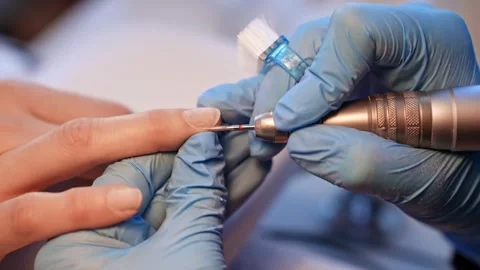 Close-up of a gloved nail technician shaping a natural fingernail with an Vidéo 333655514