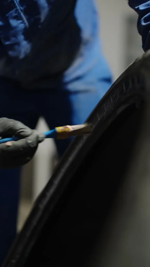 Close-up of a gloved technician applying adhesive with a brush along the bead Stock Footage 334179669