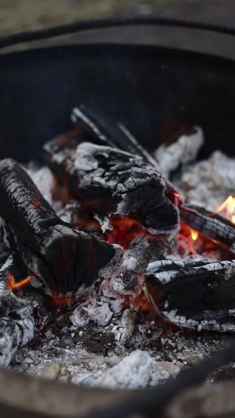 Close-up of glowing embers and burning logs in a dark fire pit Stock Footage 337106084