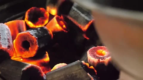 Close-up of Glowing Hexagonal Charcoal Briquettes Burning in Barbecue Grill Stockbeeldmateriaal 338213075