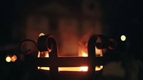 Close up of glowing iron brazier with flames and smoke at night, creating Stock Footage 283063963