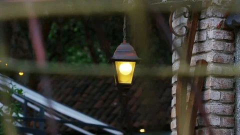 Close-up of a glowing lantern that hangs on a stone wall, on a metal mount. 스톡 동영상 104924211