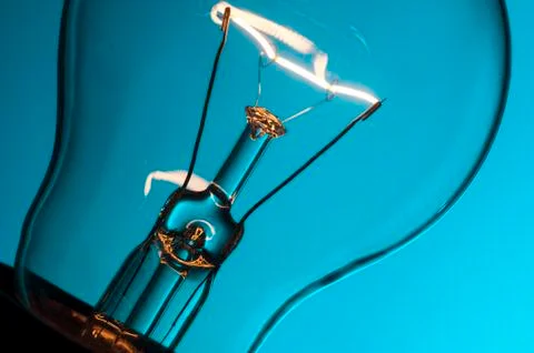 Close up glowing light bulb on blue background Stock Photos