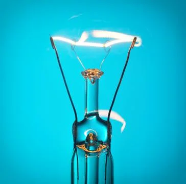 Close up glowing light bulb on blue Stock Photos