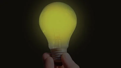 Close-up of a glowing light bulb flickering against black background. Symbolic Vídeos de archivo 337944876