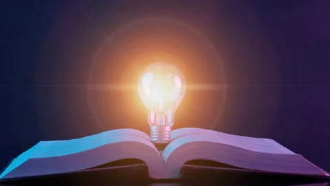 Close up of glowing light bulb on the open book. Stock Footage 236296843