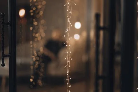 Close up of glowing string lights with warm bokeh effect in festive interior Stock Photos