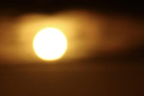 Close up of glowing sun behind dark clouds during golden sunset Stockfoto's