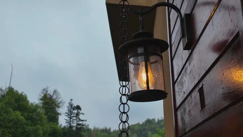 Close-up of Glowing Vintage Lantern and Rain Chain on Wet Cabin Exterior Stock Footage 335026127