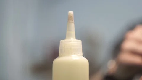 Close-up of glue bottle spout. Tanner removes the cap from the bottle. Bonding Stock Footage 104927861