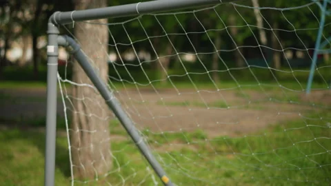 Close-Up of Goal Post as a Ball is Shot into the Net in a Grassy Field Stock-Footage 284817685