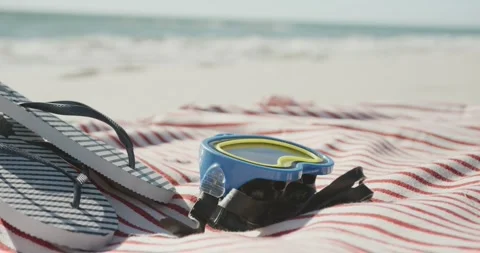Close up of goggles, flip flops and towel on beach, in slow motion, with copy Stock Footage 335866271