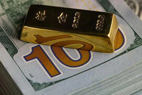 Close Up Gold Bar Lying on Stack of New US One Hundred Dollar Bills Stock Photos