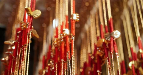 Close-up of gold chains hanging in row from ceiling inside Buddhist temple Stock Footage 222800289