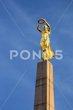 Close-up of gold statue on top of the Monument of Remembrance against blue sky Stock Photos
