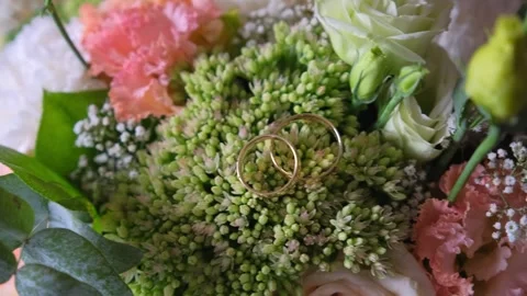 Close-up of gold wedding rings resting on floral bouquet Video stock 342135252